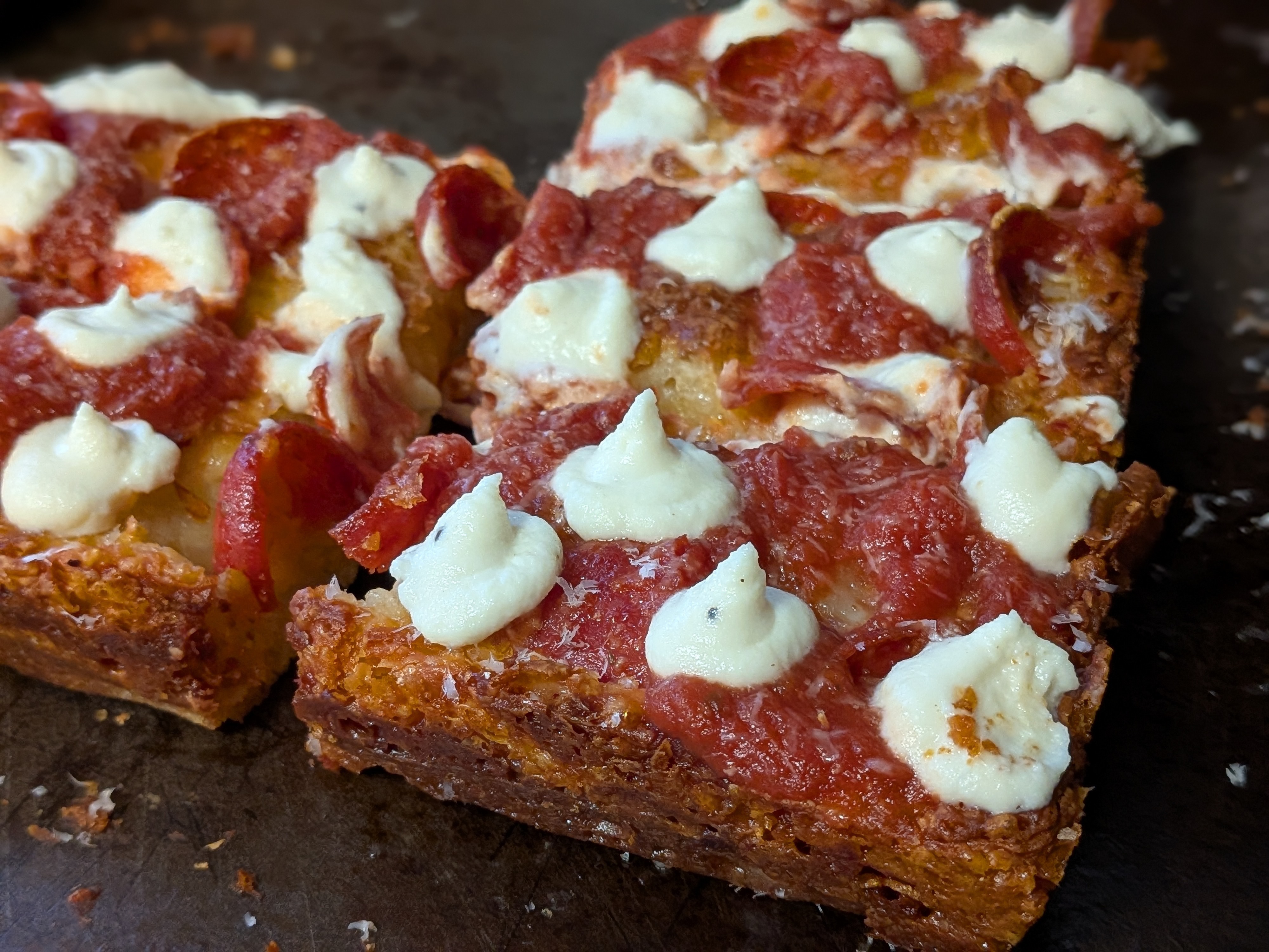 Detroit-style pizza with cup-and-char pepperoni, dollops of fresh ricotta added after baking, and homemade jalapeno hot honey, with deeply caramelized frico cheese edges