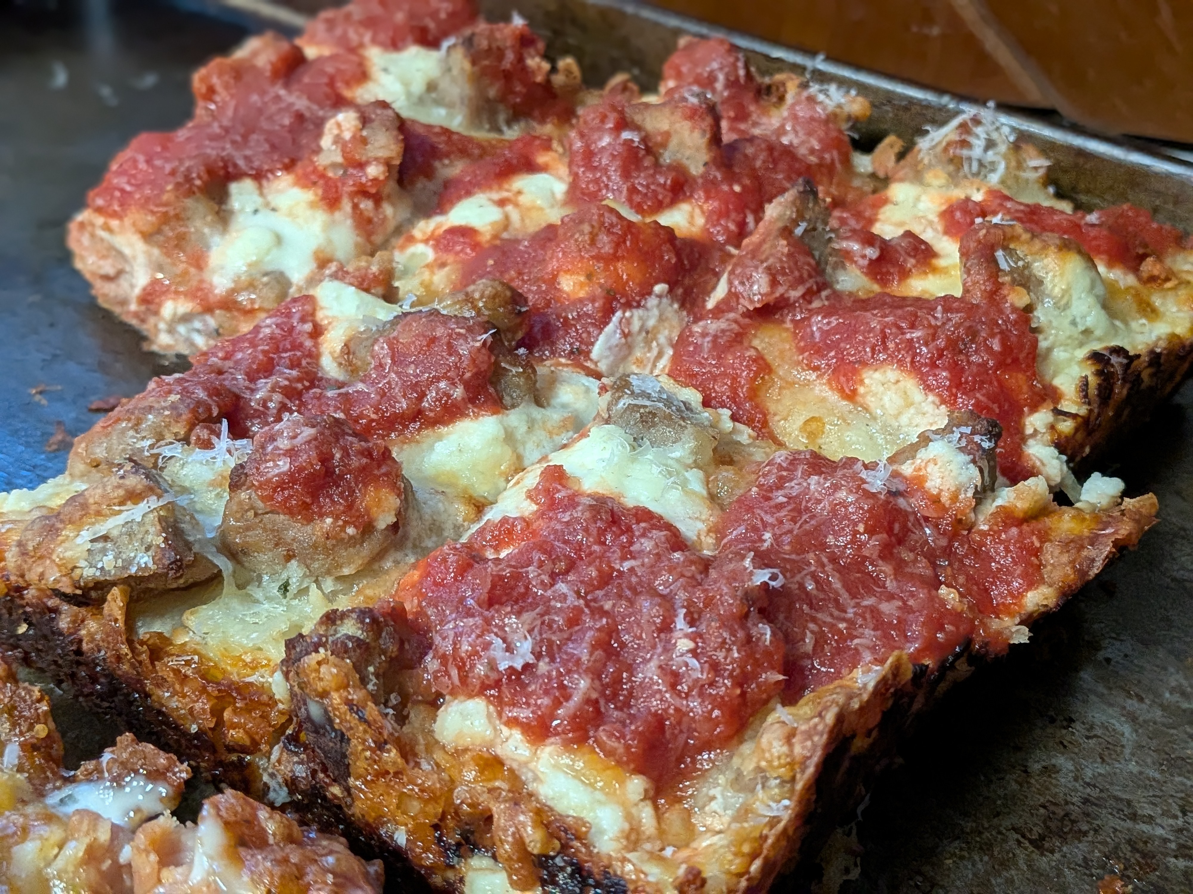 Detroit-style pizza with diced meatballs and ricotta baked into the cheese layer, finished with the classic Detroit red sauce stripes on top
